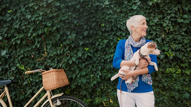 Kvinde og en hund med en hæk i baggrunden